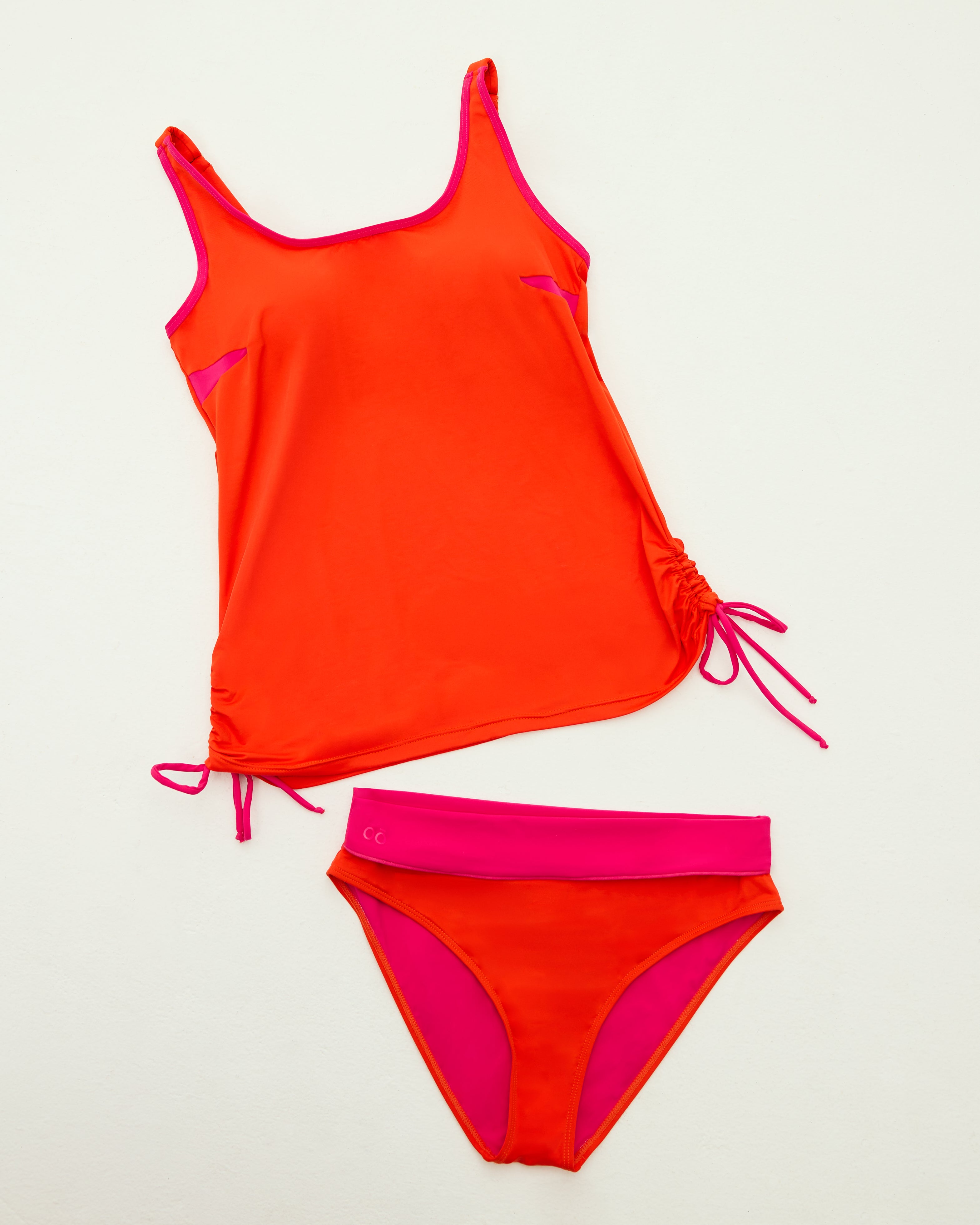 Flat lay of the orange Ikonō tankini and matching high-waist bottom, featuring adjustable drawstring detail for a customizable fit and comfort.