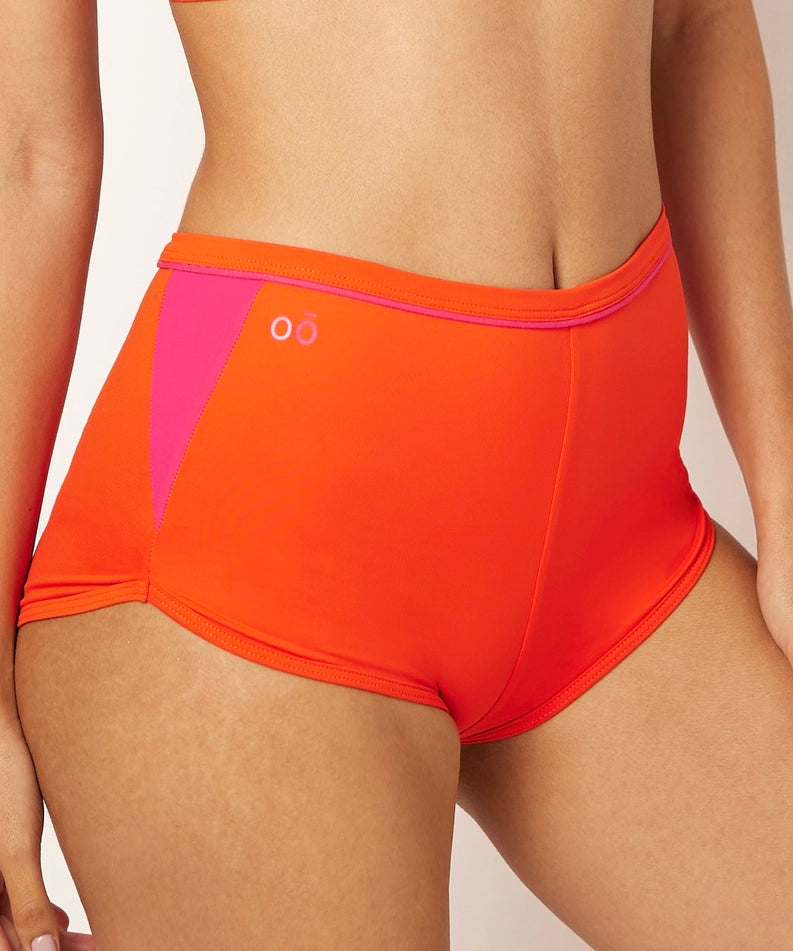 Ikonō’s orange high-waist shorty bikini, perfect for water sports, Pilates, or yoga. Made with recycled materials and UPF50+ protection, combining comfort, style, and support for every woman.