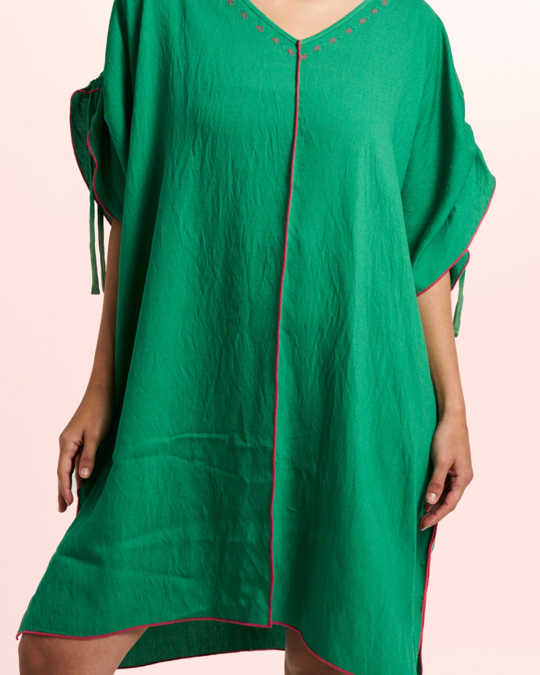 Green dress with red trim on a pink background