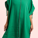 Green dress with red trim on a pink background