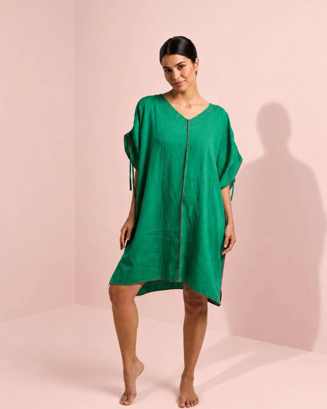 Woman wearing a green dress against a pink background
