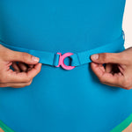 Maillot ikonō Allure Bleu Vert Emeraude, modèle de face en studio, zoom sur ceinture amovible et logo rose signature